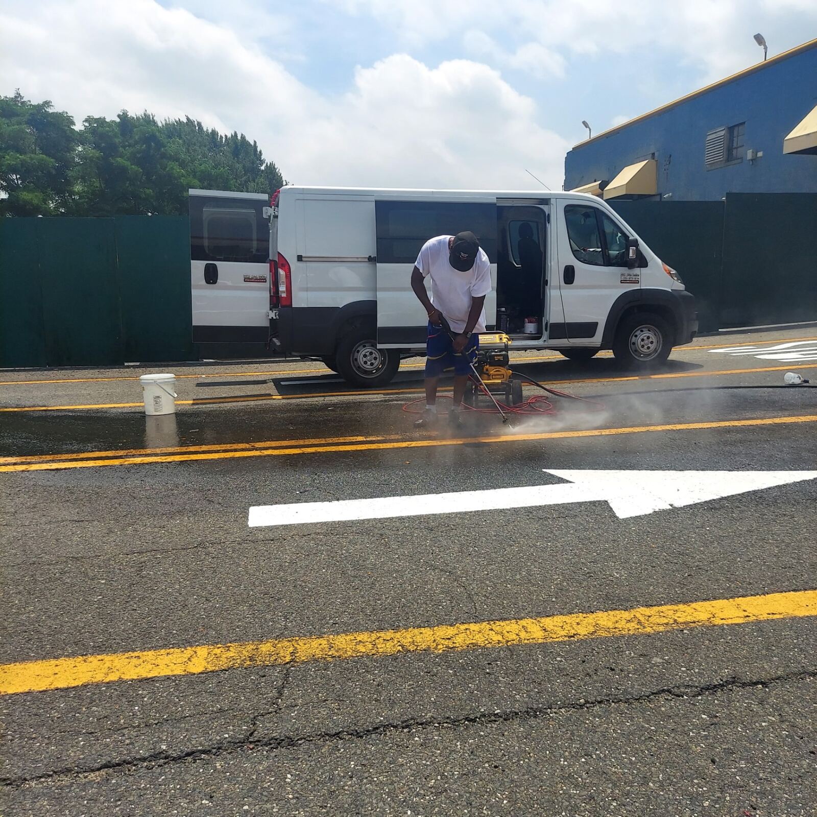 Crew member pressure washing a city street next to the service van